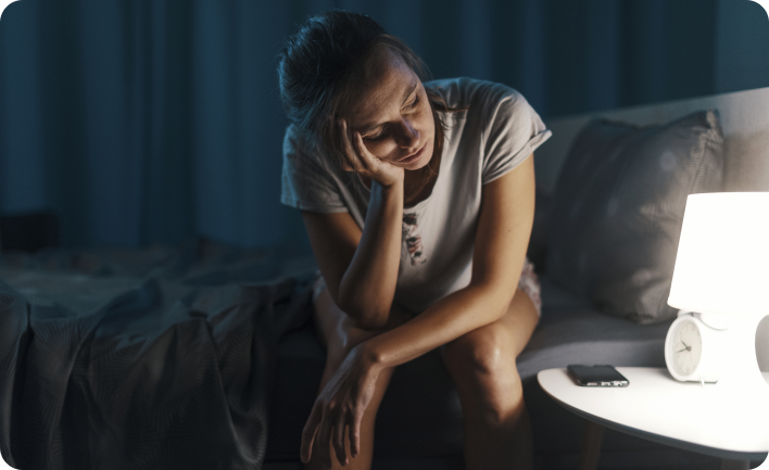 photo d'une femme assise sur son lit qui regarde sa lampe de chevet